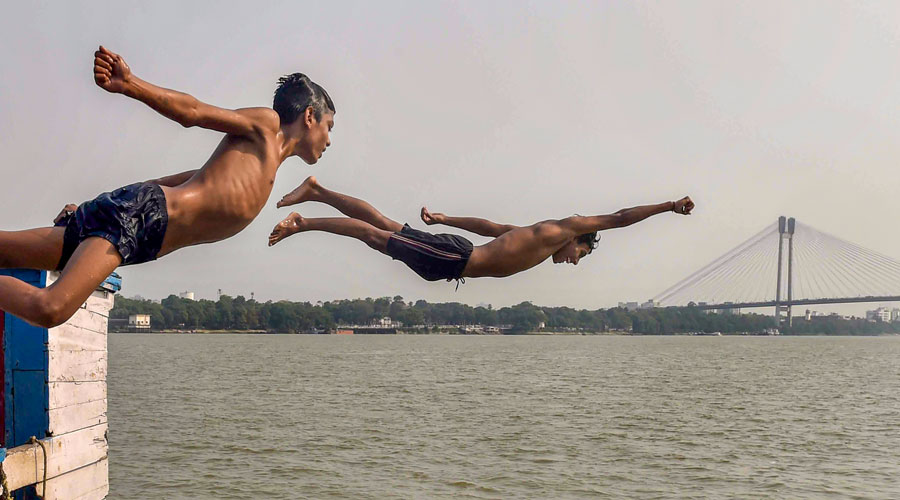 Boys jump into the Ganga River to beat the heat during a hot summer day, in Kolkata