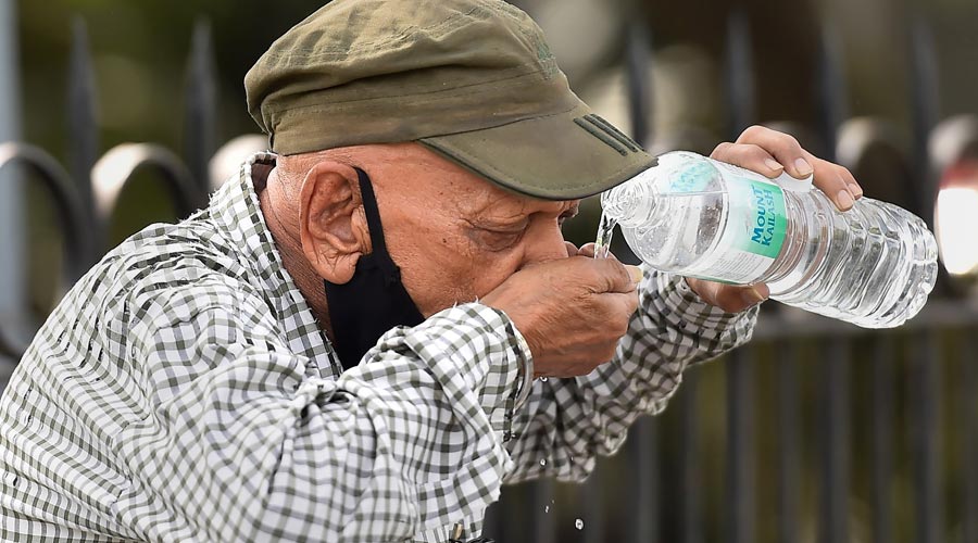 A pedestrian quenches his thirst on a hot summer day, at Cannaught Place in New Delhi
