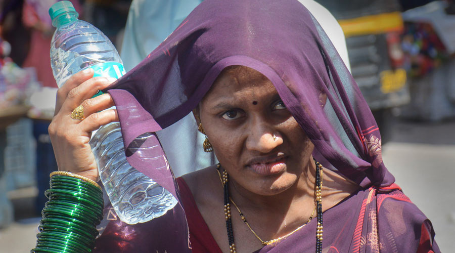 A woman covers her head with a cloth to avoid the scorching heat on a hot summer day in Thane