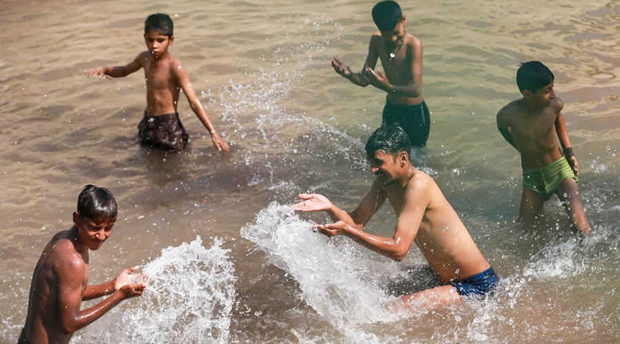 Boys play in the cooler waters of a canal to beat the heat, on a hot summer day, in Jammu