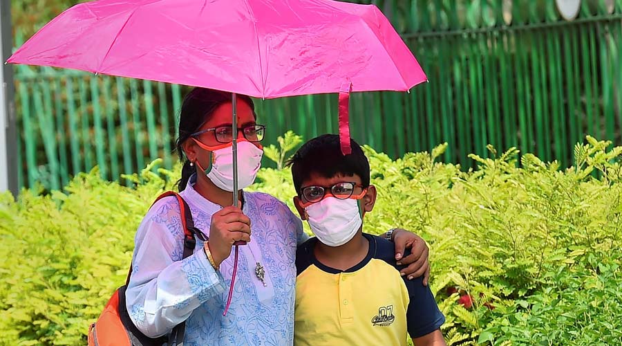 Pedestrians use an umbrella to shield themselves from the scorching sun on a hot summer day, at Cannaught Place in New Delhi