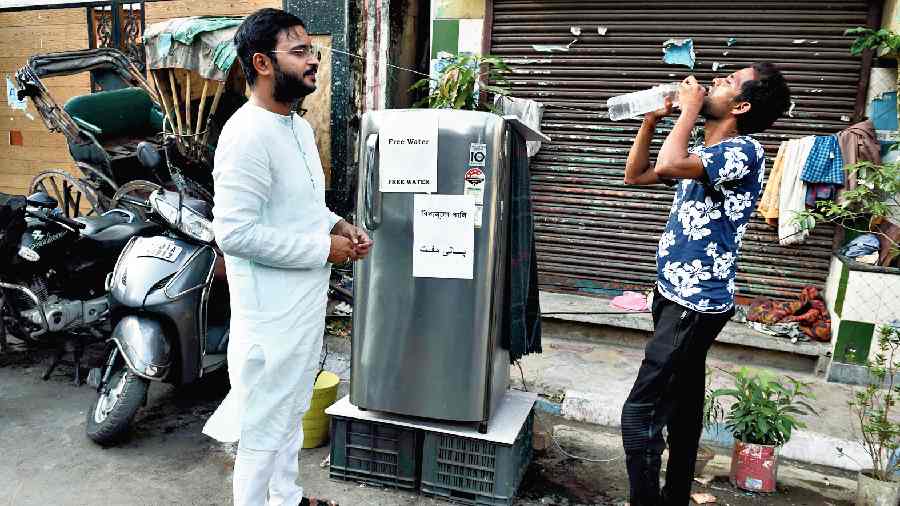 Md Tauseef Rahman offers water from the fridge he has set up outside his Alimuddin Street home. 