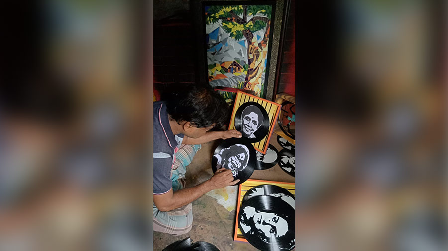 An artist employed by Purba Putiari Pragati Sangha paints singer Nirmala Mishra's portrait on a record 