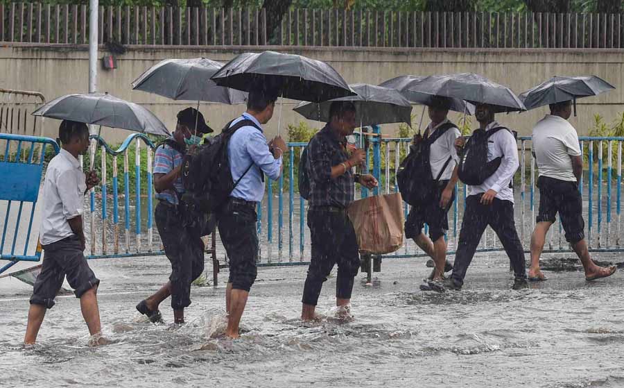 Office-goers walk through ankle-deep water after a shower in Kolkata on Tuesday. July, the rainiest month in Kolkata, ended with a near 30 per cent deficit this year, according to IMD 