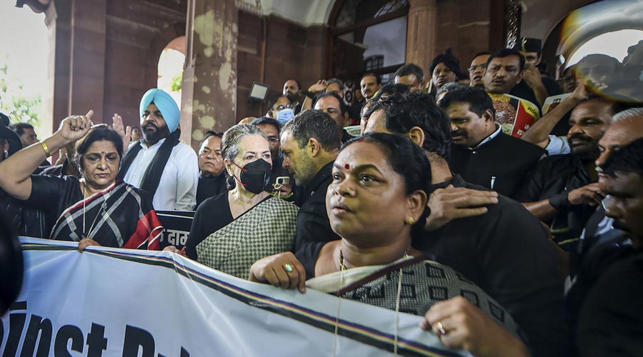 Congress President Sonia Gandhi along with Rahul Gandhi standing with the women MPs of the party holding a banner outside gate number 1 of Parliament.
