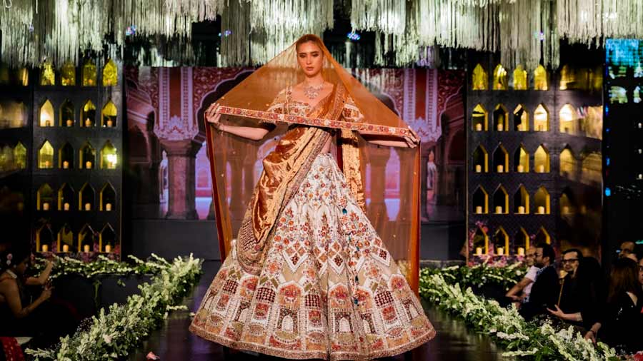 A model wears an unusual earth-toned lehenga with extraordinary zari work