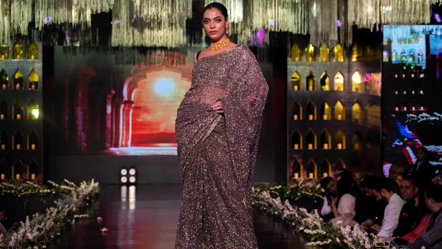 A model wears a dramatic midnight-hued sari with gold jewellery