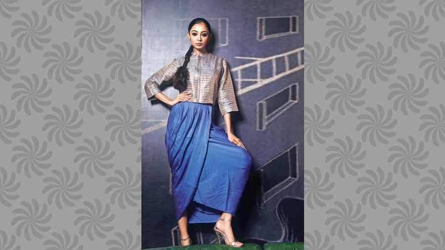 An Indo-western Benarasi outfit in metallic shades, perfect for a non-traditional festive look. The geometric-pattern zipper jacket is paired with a pre-pleated dhoti skirt for a subtle-glam, easy-to-carry festive look.