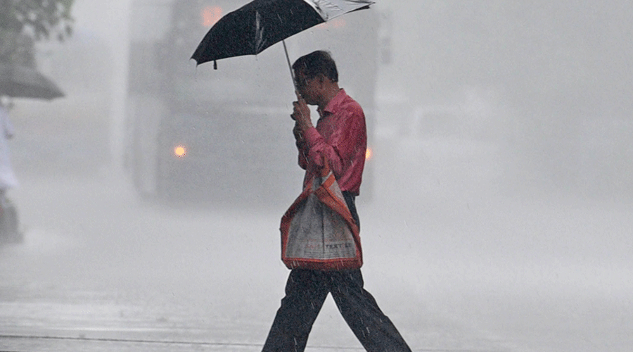A pedestrian caught in rain on JL Nehru Road on Monday.