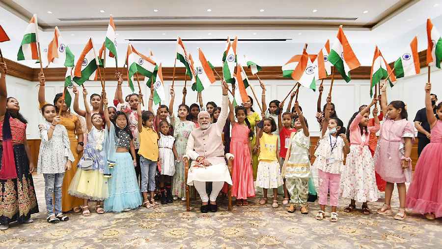 Prime Minister Narendra Modi waves tricolour with girls who tied rakhi to him in New Delhi