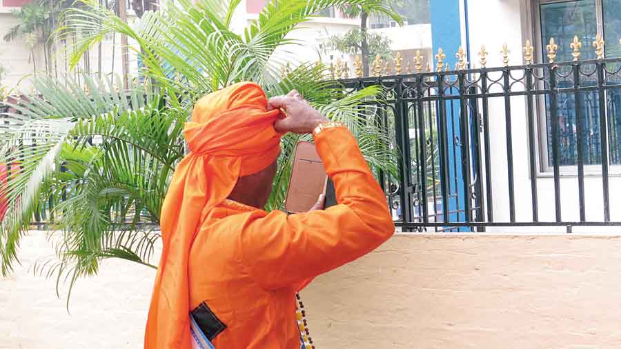 What is the baul thinking while fixing his turban looking at his cellphone?