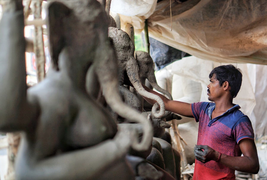 An artisan at Patuapara in Kalighat works on Ganesh idols on Tuesday. Only a fortnight is left before Ganesh Chaturthi when these idols would be transported to pandals and households for worship