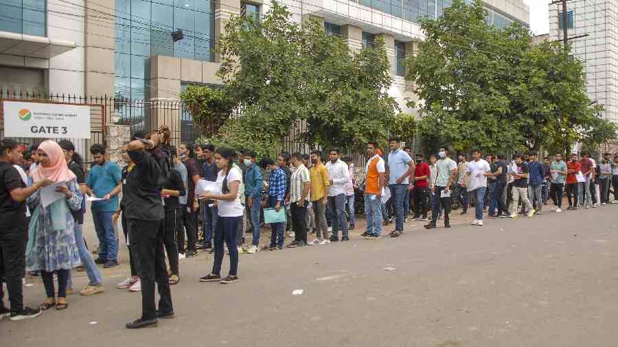 Students wait in a queue to appear in Common University Entrance Test, outside a centre, in Noida on Wednesday