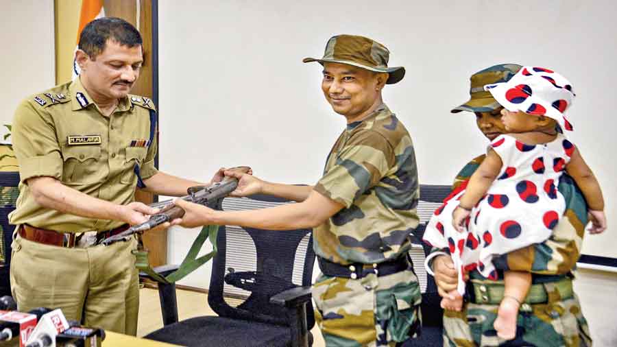 Kailash Koch hands over his weapon to DGP Manoj Malaviya in Calcutta on Thursday. On the right is Koch’s wife Jugli. 