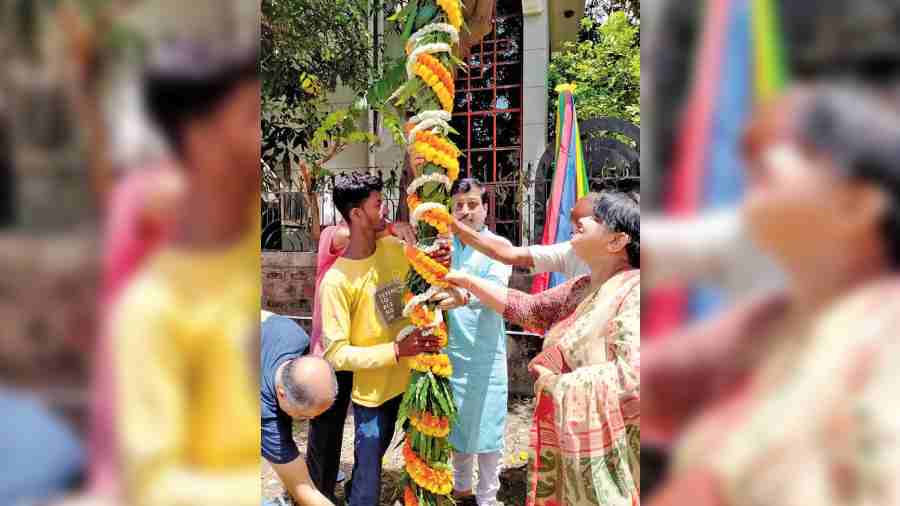 Local councillor Sabyasachi Dutta holds up the bamboo pole along with others