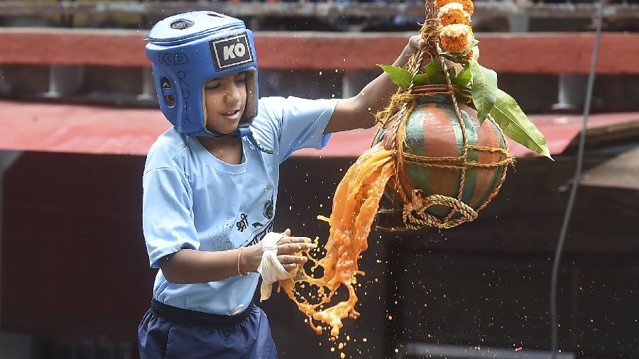  A child atop a human pyramid breaks a dahi-handi, suspended in the air at Dadar in Mumbai