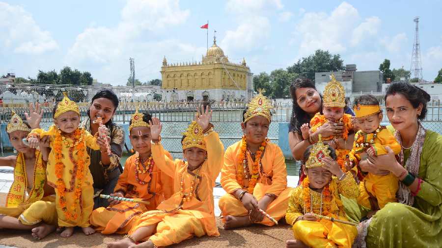 Children dressed as Lord Krishna pose for photos at Durgiana Temple in Amritsar