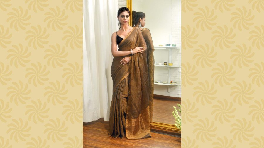 The model is displaying a handwoven tissue linen sari in bronze and gold, with golden border. Price: Rs 5,200