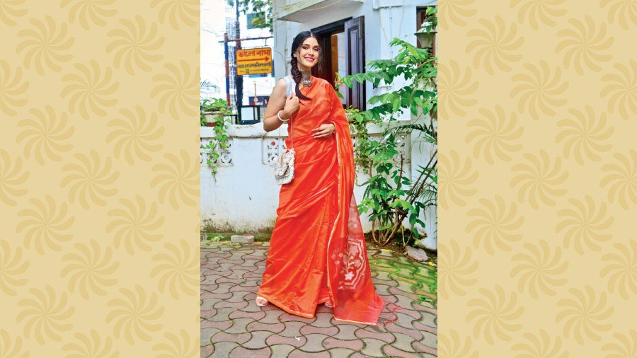The model is wearing a resham silk sari in bright orange and rust with jamdani pallu. Price: Rs 7,350