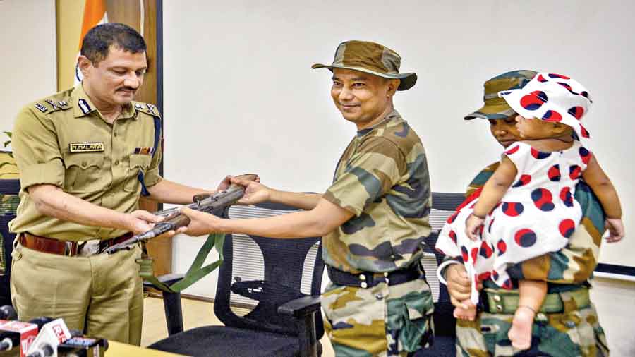 Kailash Koch hands over his weapon to DGP Manoj Malaviya in Calcutta on Thursday. On the right is Koch’s wife Jugli. 