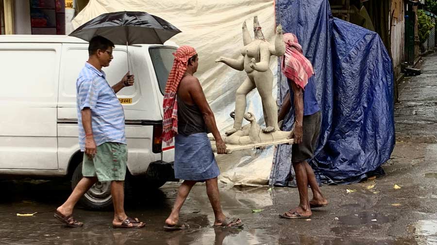Artisans carry a half-finished idol of Kali to safety on a rainy afternoon at Kumartuli on Friday, August 19. 