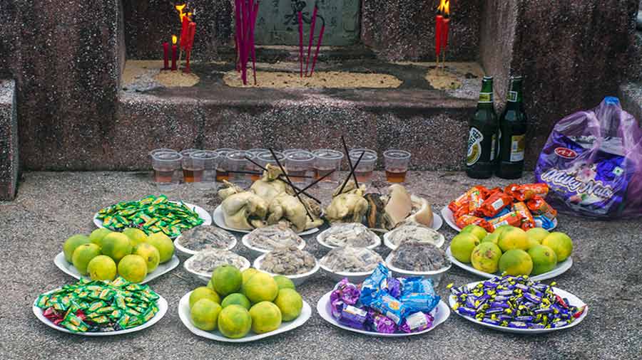 A feast of fruits, cadies, wine, meat and other food laid in front of a grave