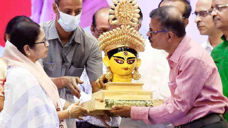 Chief minister Mamata Banerjee being presented with a bust of Goddess Durga during the coordination meeting with puja organisers at Netaji Indoor Stadium on Monday. 