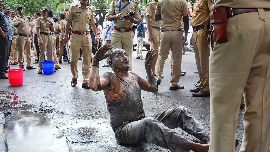 Police personnel near Subhash Bhanudas Deshmukh after he tried to commit suicide by setting himself on fire outside the Vidhan Bhavan, in Mumbai, Tuesday, Aug. 23, 2022.