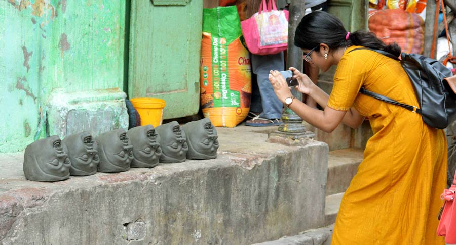 A girl clicks photographs of clay heads being sun-baked  on Thursday morning.