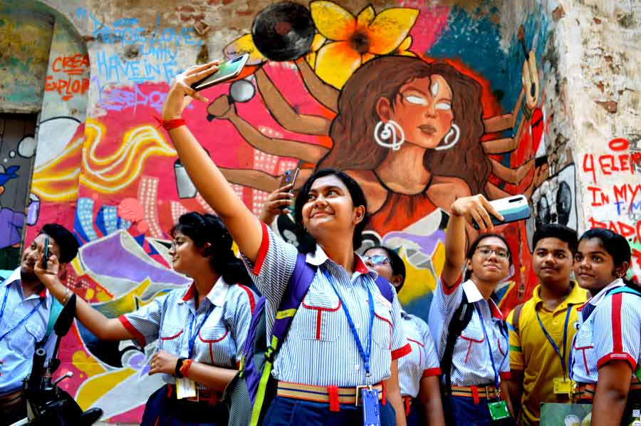 Schoolchildren click selfies in front of a mural depicting modern-age Durga at Kumartuli on Thursday.