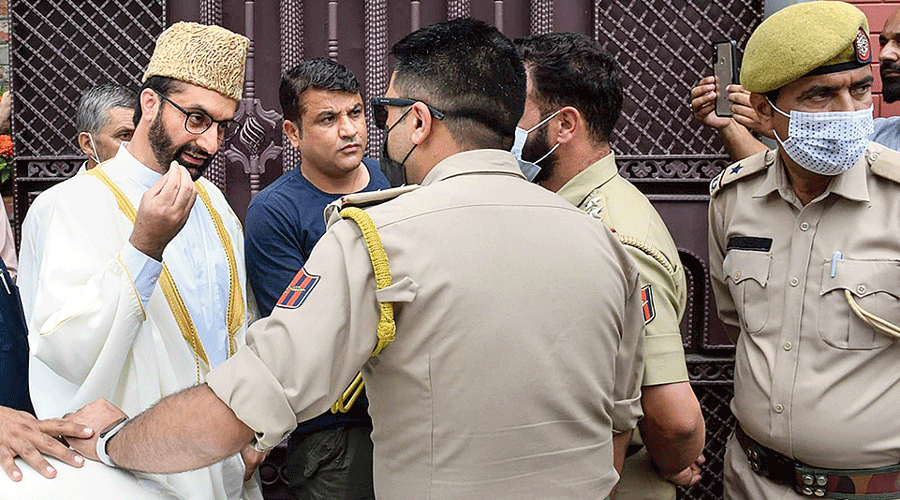 Mirwaiz Farooq speaks to policemen after being  barred from stepping out  of his house in Srinagar on Friday.