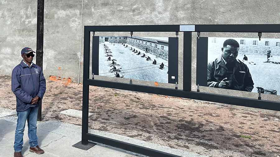 Peter Khube stands next to a picture of Robben Island prisoners at work 