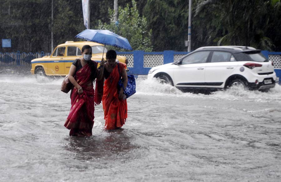 Two women wade through a waterlogged street in front of Akashvani Bhavan on Saturday.