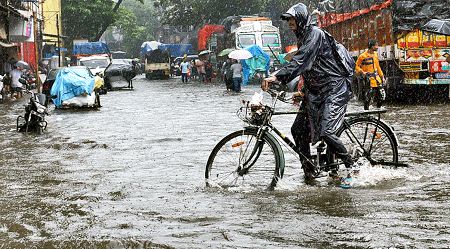 Commuters wade through a waterlogged Colootola Street in north Kolkata on Saturday afternoon. 