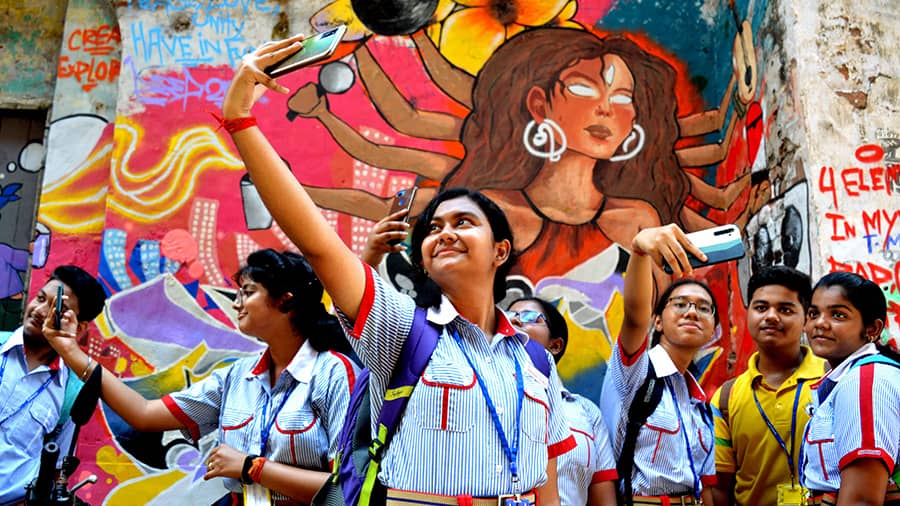 Schoolchildren click selfies in front of a mural depicting modern-age Durga at Kumartuli on Thursday, August 25.