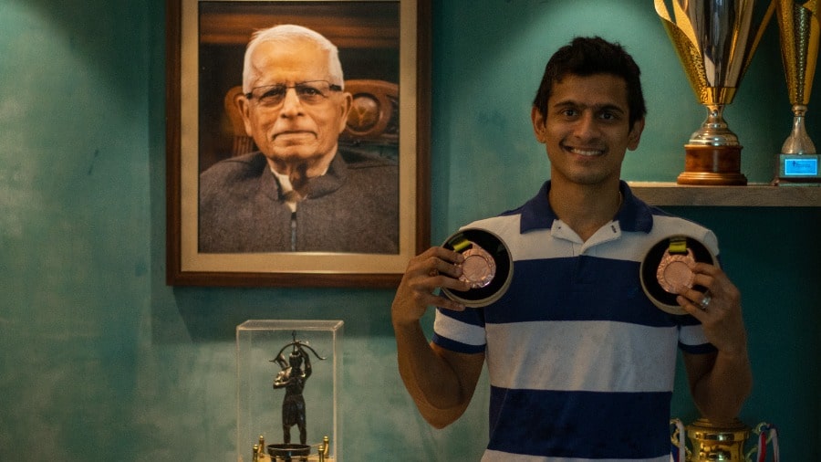 Saurav Ghosal with the two bronze medals he won at the Commonwealth Games 2022. In the photograph behind Saurav is his grandfather Sourendra Nath Ghosal, who passed away in 2020. Saurav is forever grateful to his grandfather for all his support and sacrifices  