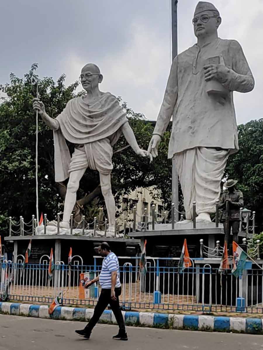 A man walks past statues of Mahatma Gandhi and Netaji Subhas Chandra Bose in north Kolkata on Tuesday afternoon.