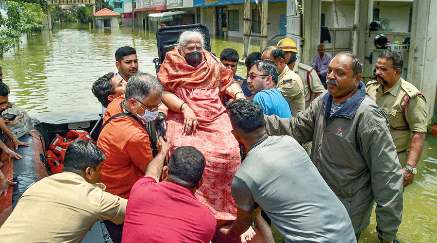 Firefighters and civil defence personnel evacuate an elderly patient on a boat from the waterlogged Rainbow Drive Layout after heavy rain at Sarjapur in Bangalore on Tuesday.