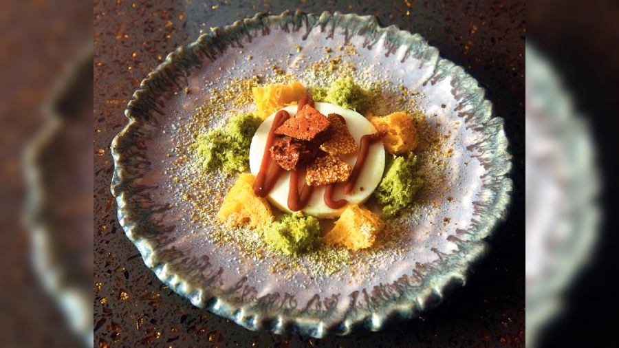 Yuzu Malai Pistachio Crumb: Art on a plate, this dessert is a break from the overtly sweet ones. This has pana cotta with caramel drizzle, orange and pistachio sponge and pistachio crumb on top. Pure indulgence!