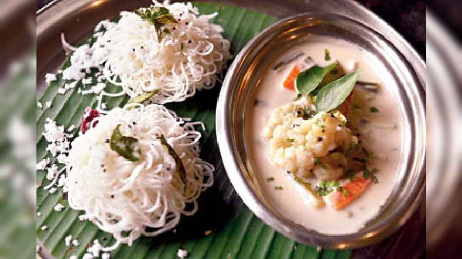 Lightweight Idiyappam rice noodles garnished with coconut, served with healthy stew made with coconut milk and fresh vegetable stock, garnished with curry leaves.