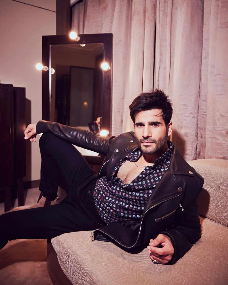 Jackets are a wardrobe staple for Karan who styled his black leather jacket with a blue printed shirt. 