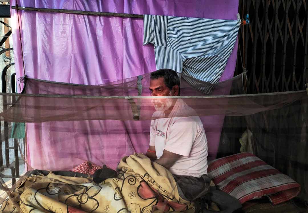 A pavement dweller sits inside a mosquito net. Even as dengue cases have started to decline, Kolkatans are still taking basic precautions against the vector-borne disease