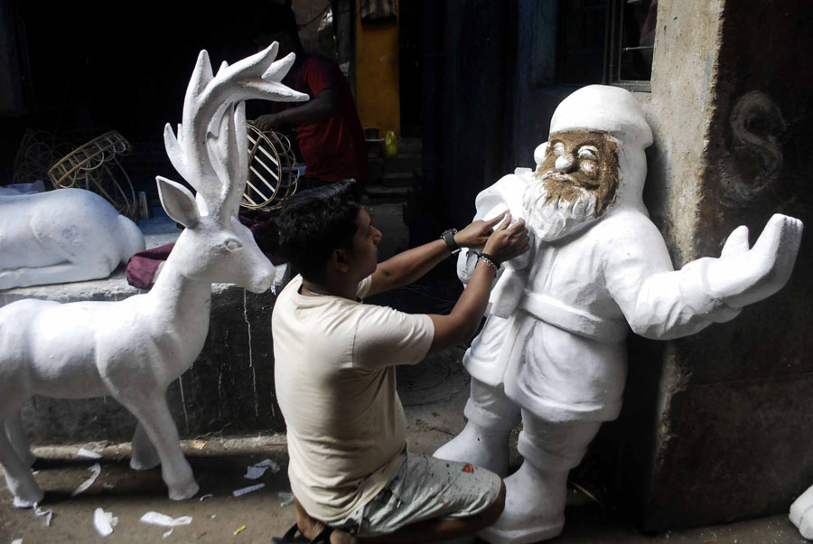 As the city gears up for Christmas celebrations, an artist prepares a Santa Claus sculpture at Dompara 