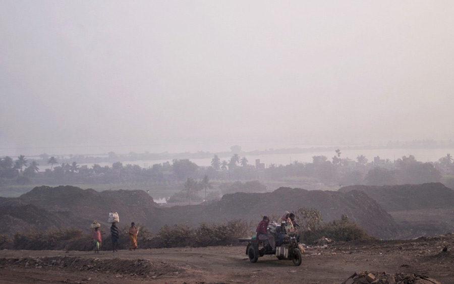 People leave for work against the backdrop of a smog-enveloped horizon in the Dhapa landfill area. The city has been experiencing poor-quality air due to high levels of air pollution for the last couple of weeks