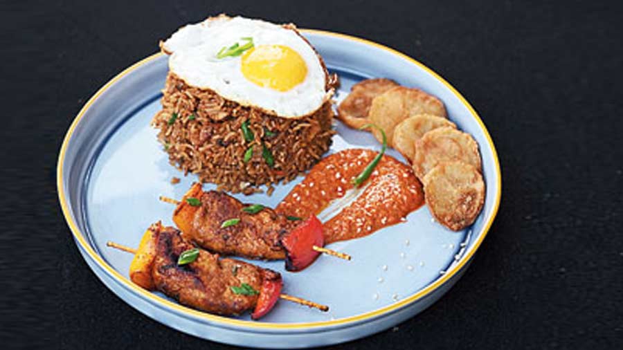 Nasi Goreng: Indonesia's take on fried rice that is tossed in soy sauce, with vegetables and succulent meat pieces, is served with spicy chicken skewers and potato fries.