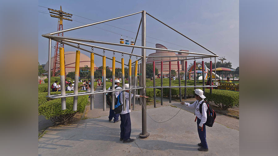 Student bangs hollow pipe to hear the sound at science city garden