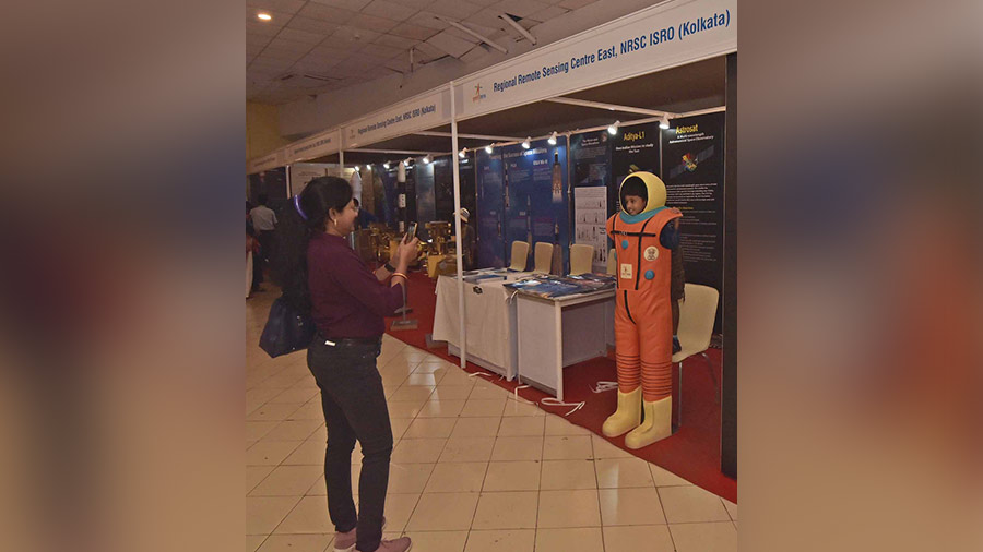 A kid pose with space suit as his mother takes a photo