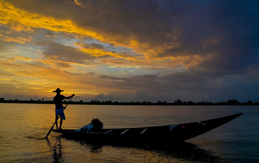 A fisherman rows his boat across the Hooghly river during sunset in Nadia district on  Friday, Dec. 9, 2022 