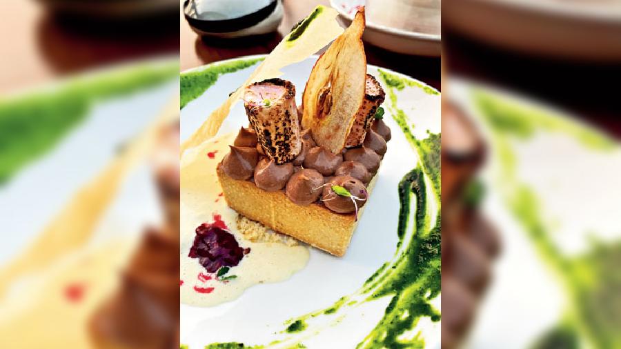 Dark Chocolate & Cumin Tart: Conclude your meal with olive sponge-infused cumin tart, that’s garnished with dark chocolate inside, marshmallow, dehydrated apple and fresh sweet basil sauce on the side