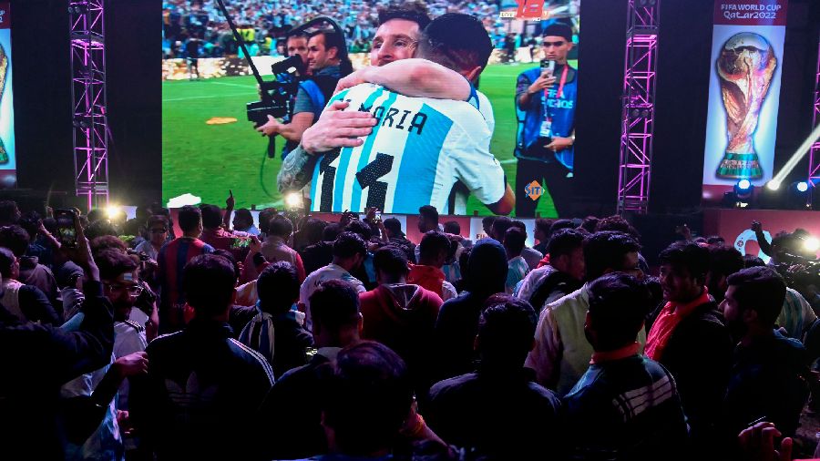 Argentina fans celebrate after Lionel Messi scores a goal as they are watching on a large screen. 